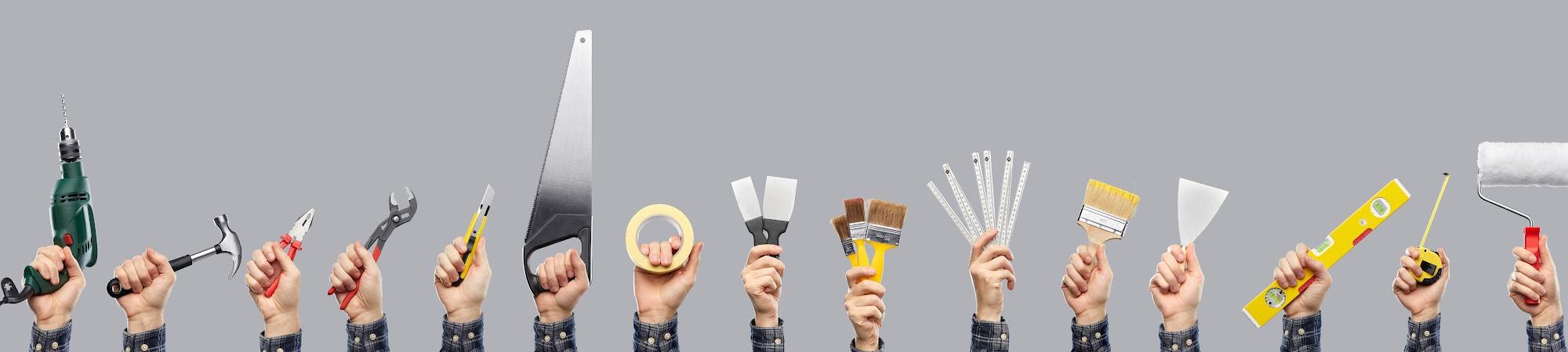 Hands holding various tools and paintbrushes